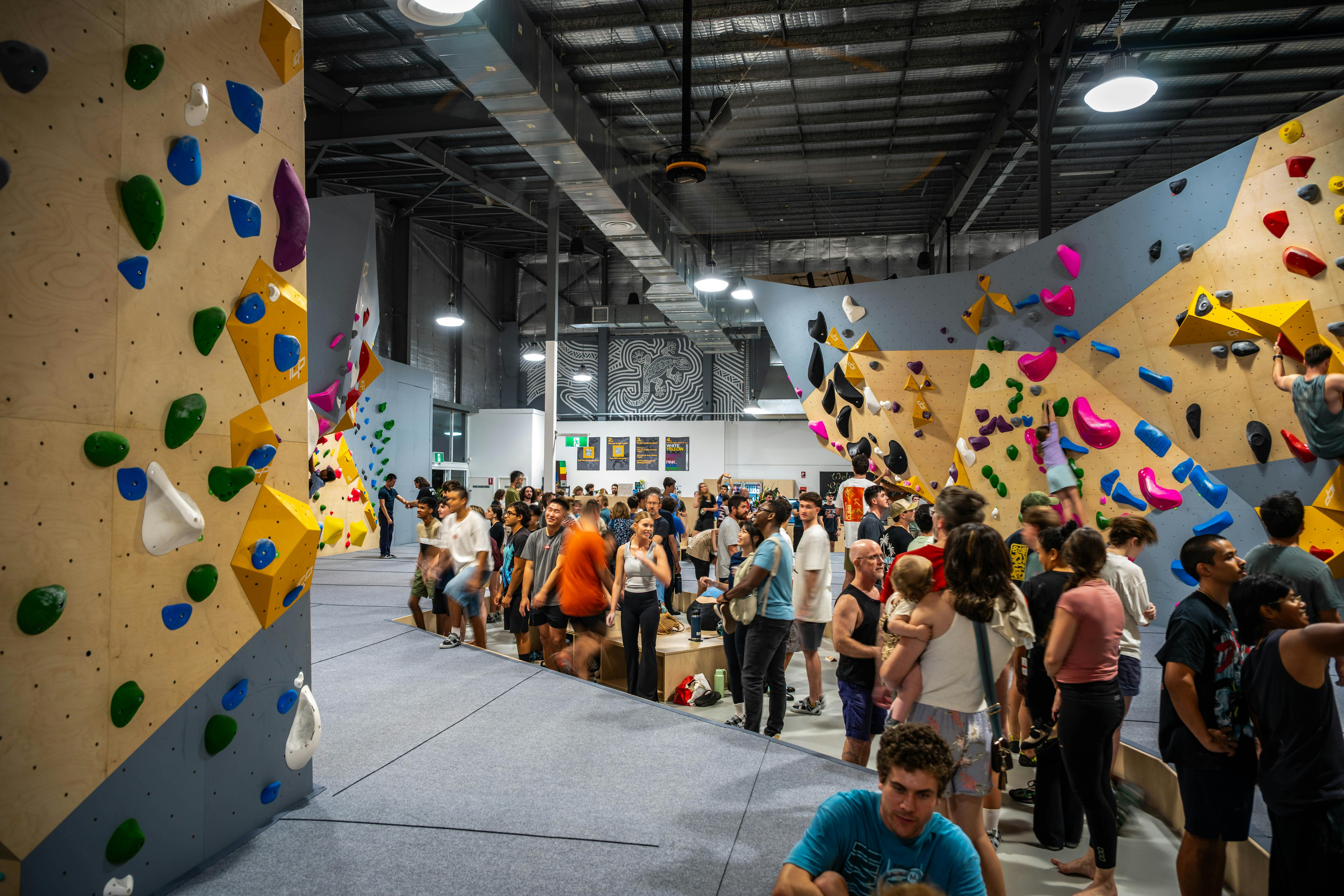 photo of people in bouldering gym main hall participating in the sport and observing others
