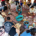 people sitting in a circle concentrating on a painting on bark