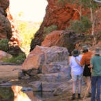 three people stand at easels outdoors painting Simpsons Gap