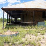 General view of the original Telegraph Station building, showing badly deteriorating woven bamboo slat screening to verandah and missing sections of low corrugated iron wall to perimeter of building.