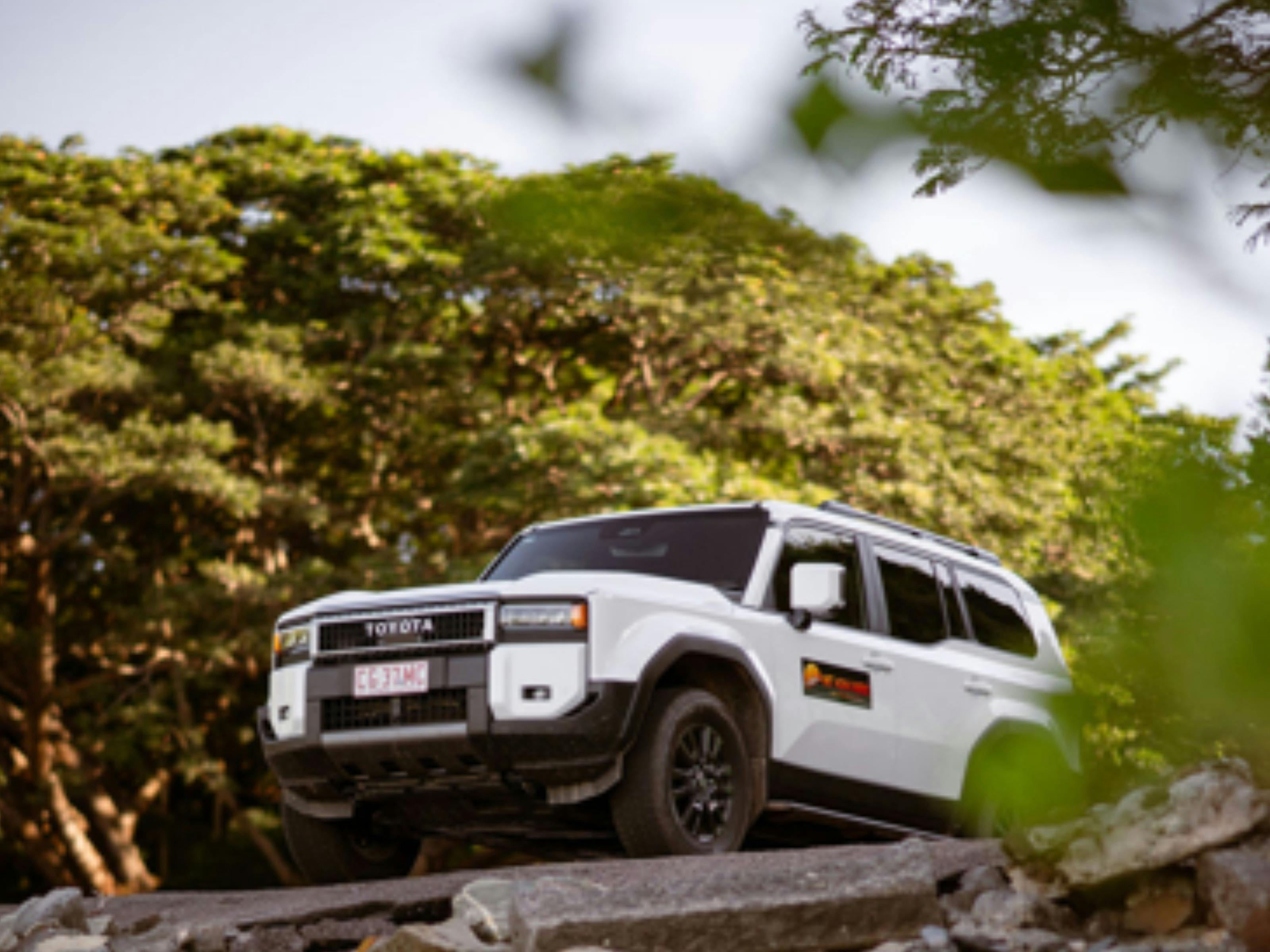 Toyota Prado parked in the NT.  Lush greenery surrounding the white vehicle