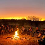 Customers sitrting around a fire as the sun sets in the background