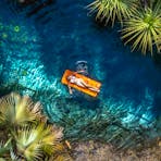 Aerial view of a woman floating on a inflatable in the Mataranka thermal pool