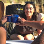 Three campers sitting around the campsite table cheering together
