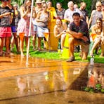 A crowd gather in a circle to watch the frog racing to seeing which frog jumps out of the circle