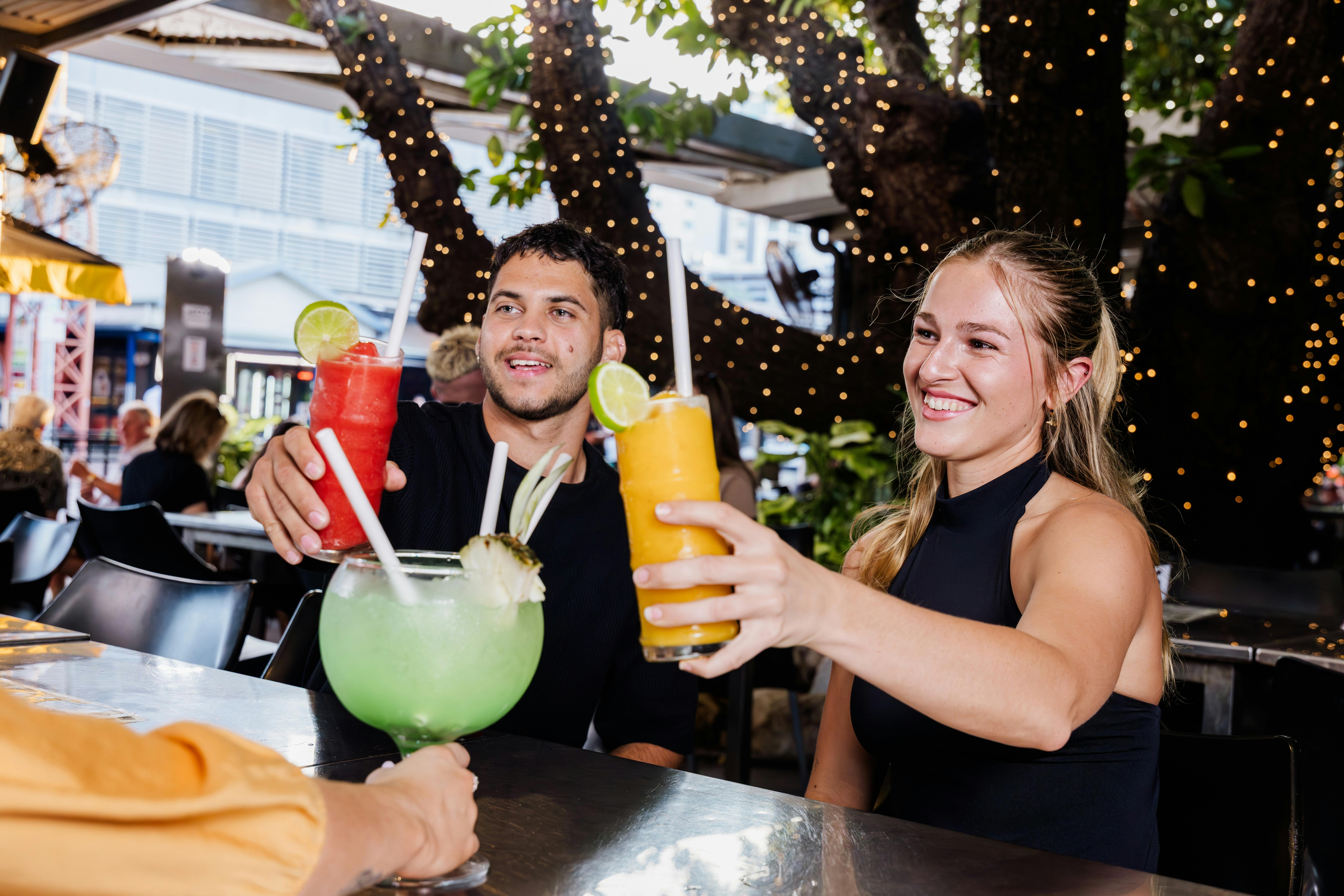 Friends enjoying cocktails. Fishbowls and daiquiris