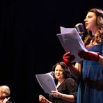 2 performers holding scripts and reading with an Auslan interpreter in the background