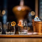 Three glasses with garnish and a bucket of ice as part of a gin tasting experience