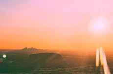 A beautiful image of sunset across the desert from a light aircraft looking at Uluru and Kata Tjuta