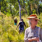 Woman stands amongst the long grass and bushlands as she explores with the group and guides