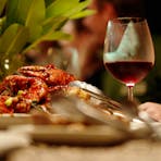 Chilli mud crab on table for a group beach dinner with a glass of wine