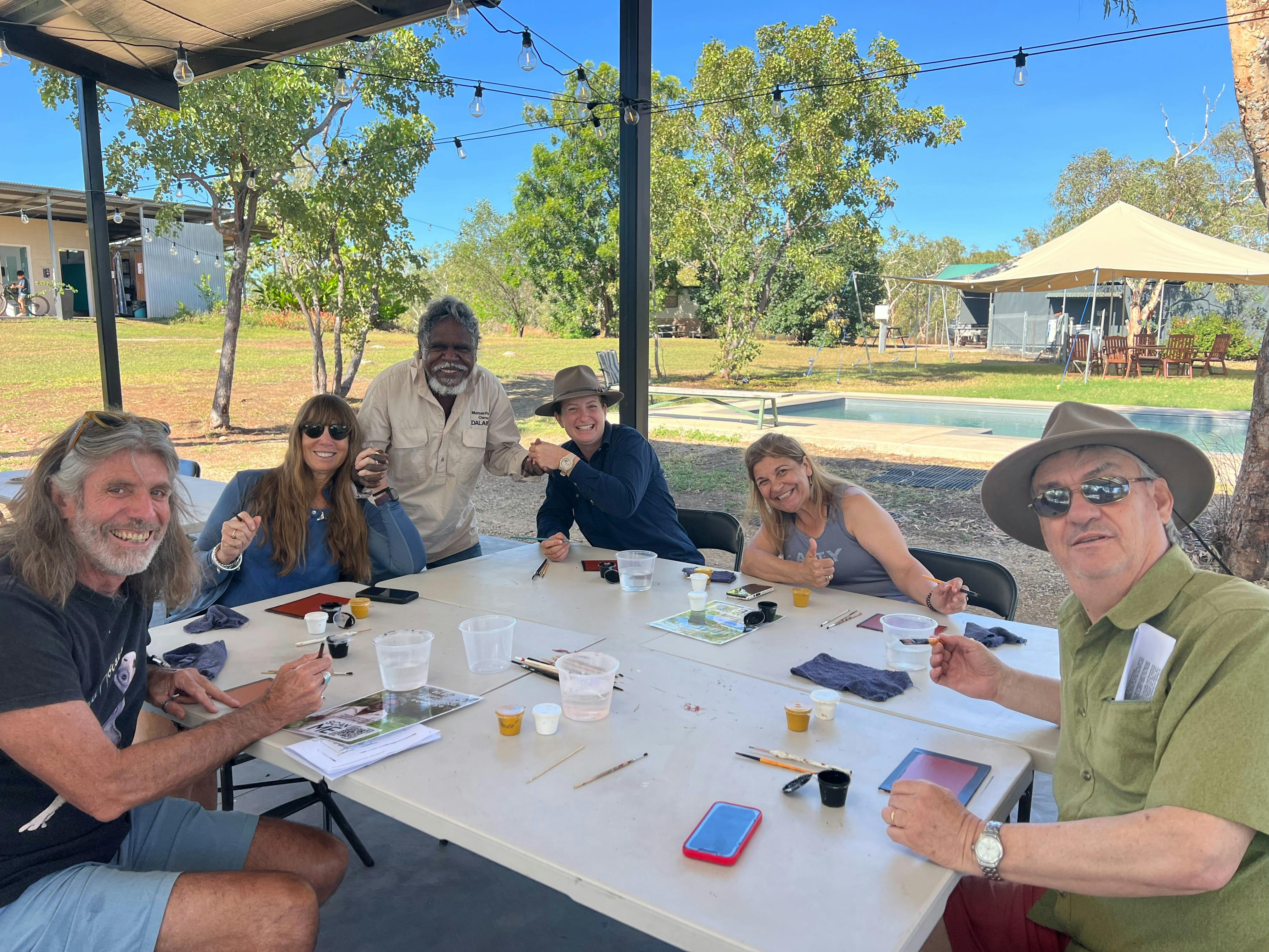 5 tourists sit at a table painting with Manuel Pamkal
