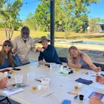 5 tourists sit at a table painting with Manuel Pamkal