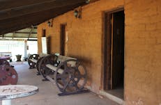 Verandah area of mud hut, with display of machinery parts