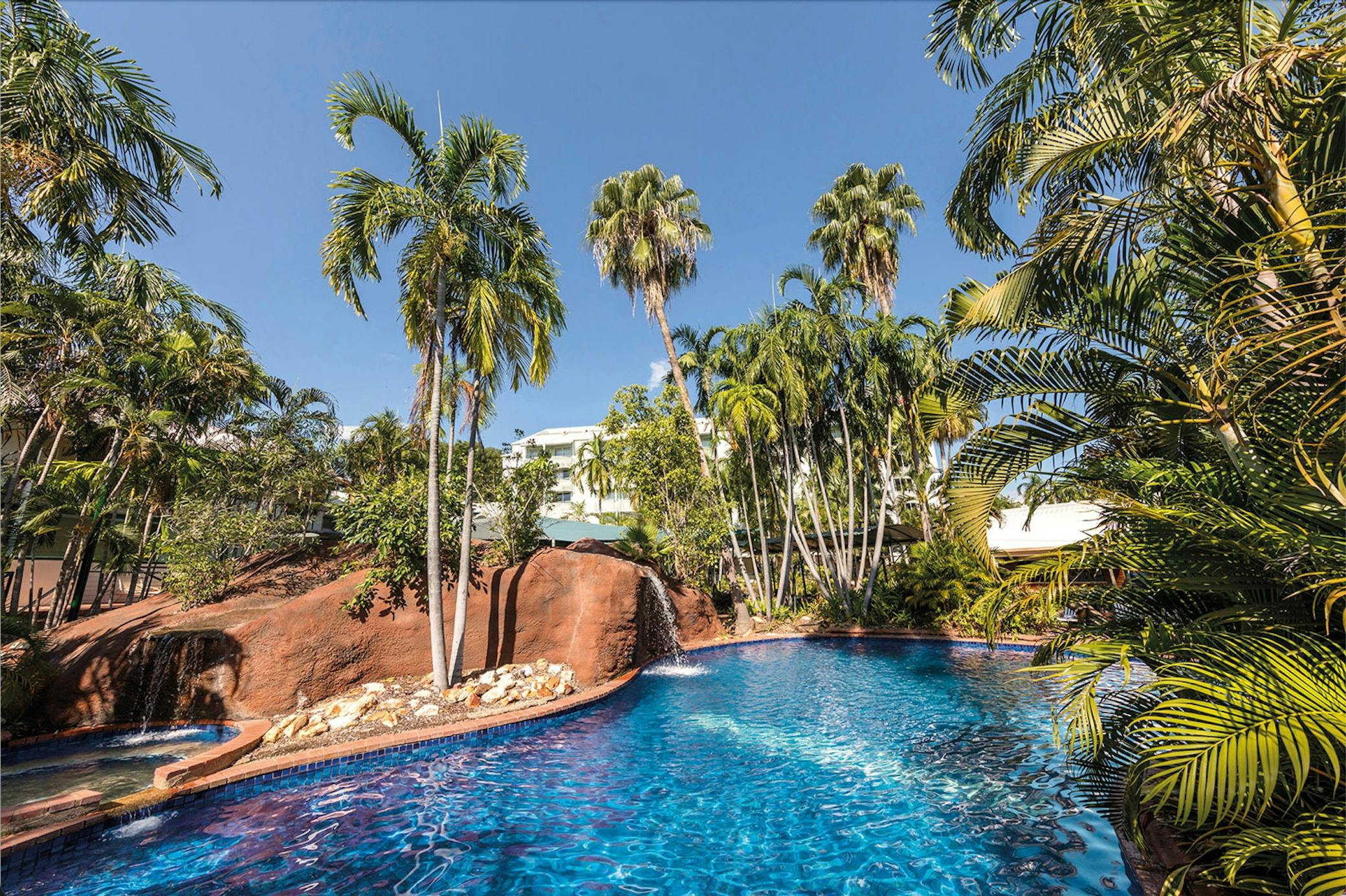 Palm-lined swimming pool with waterfall
