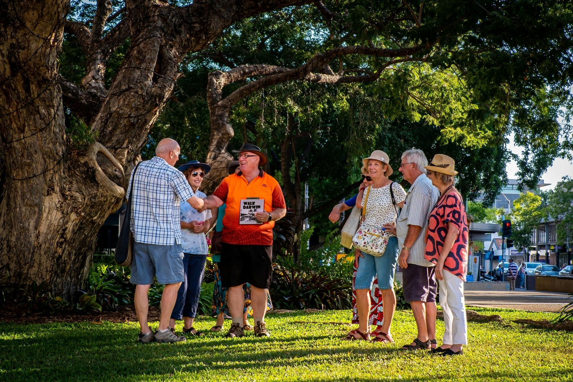 Walk Darwin guide shaking hands and welcoming guests under shady green trees
