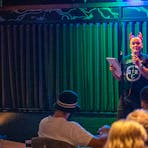 Person on stage in front of crowd talking to them