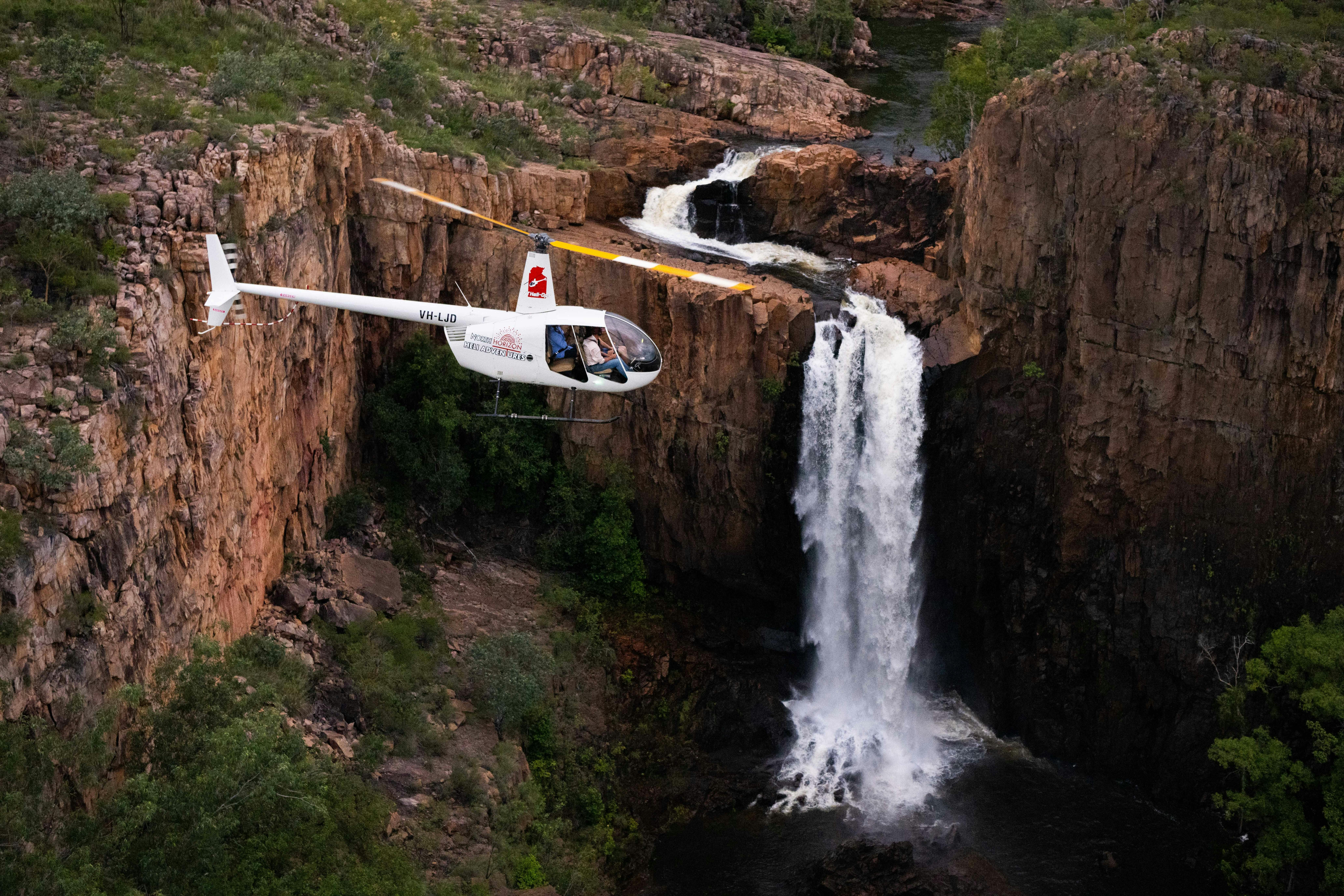Helicopter flying in front of a Nitmiluk Gorge waterfall