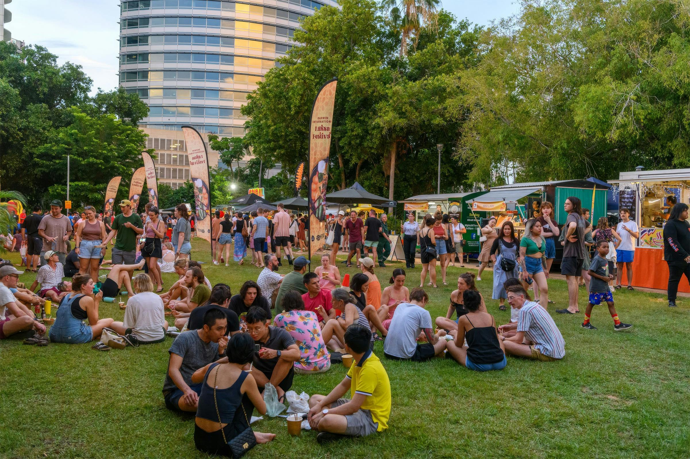 Festivalgoers relaxing on the grass among food stalls at the Darwin International Laksa Festival in