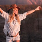 Girl stretching arms in the air smiling at the sunset in Uluru