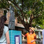Guide and guests stand before a statue of a greek woman carrying a water pot