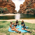 A group of friends having a picnic on the grass next to Ellery Creek Big Hole