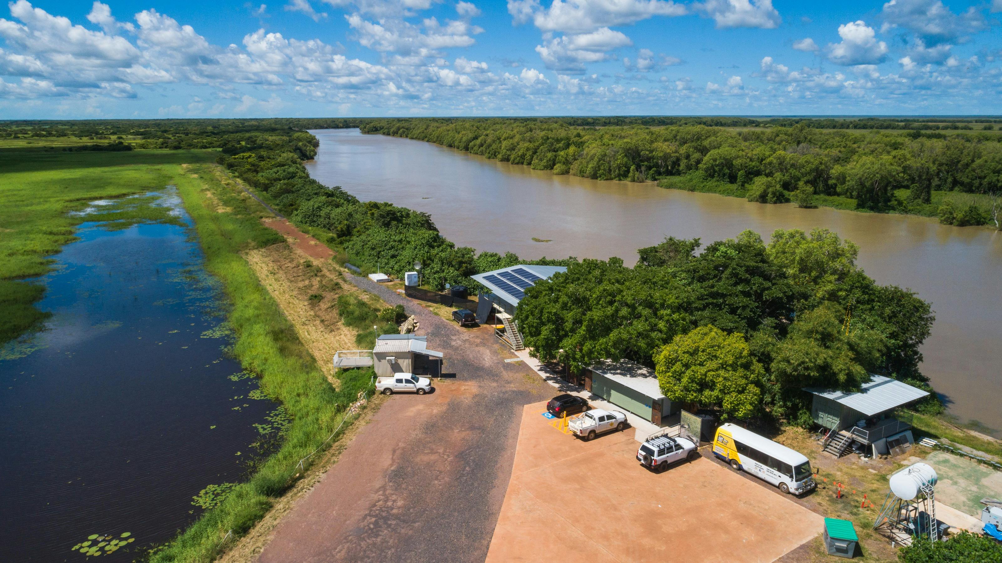 A drone showing a large carpark, and building with solar panels. The river is visible behind