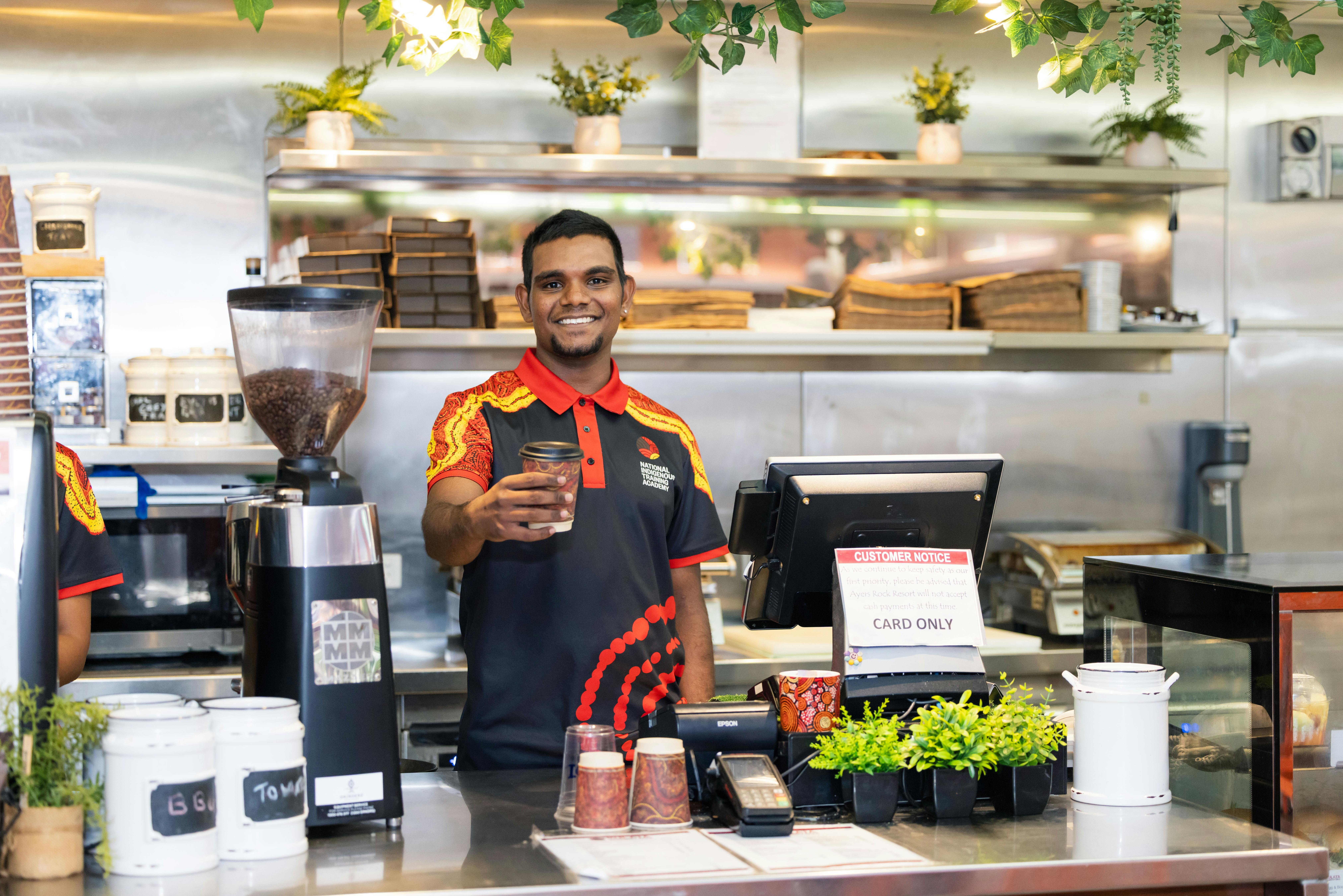 Smiling cafe staff member handing coffee to customer