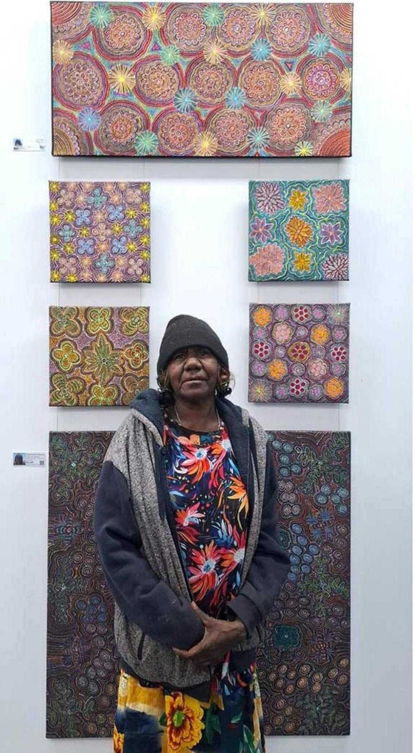 Jessie Hunter standing infront of her artwork on the feature wall.