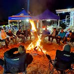 Customers sitting around a large campfire after a hard days riding