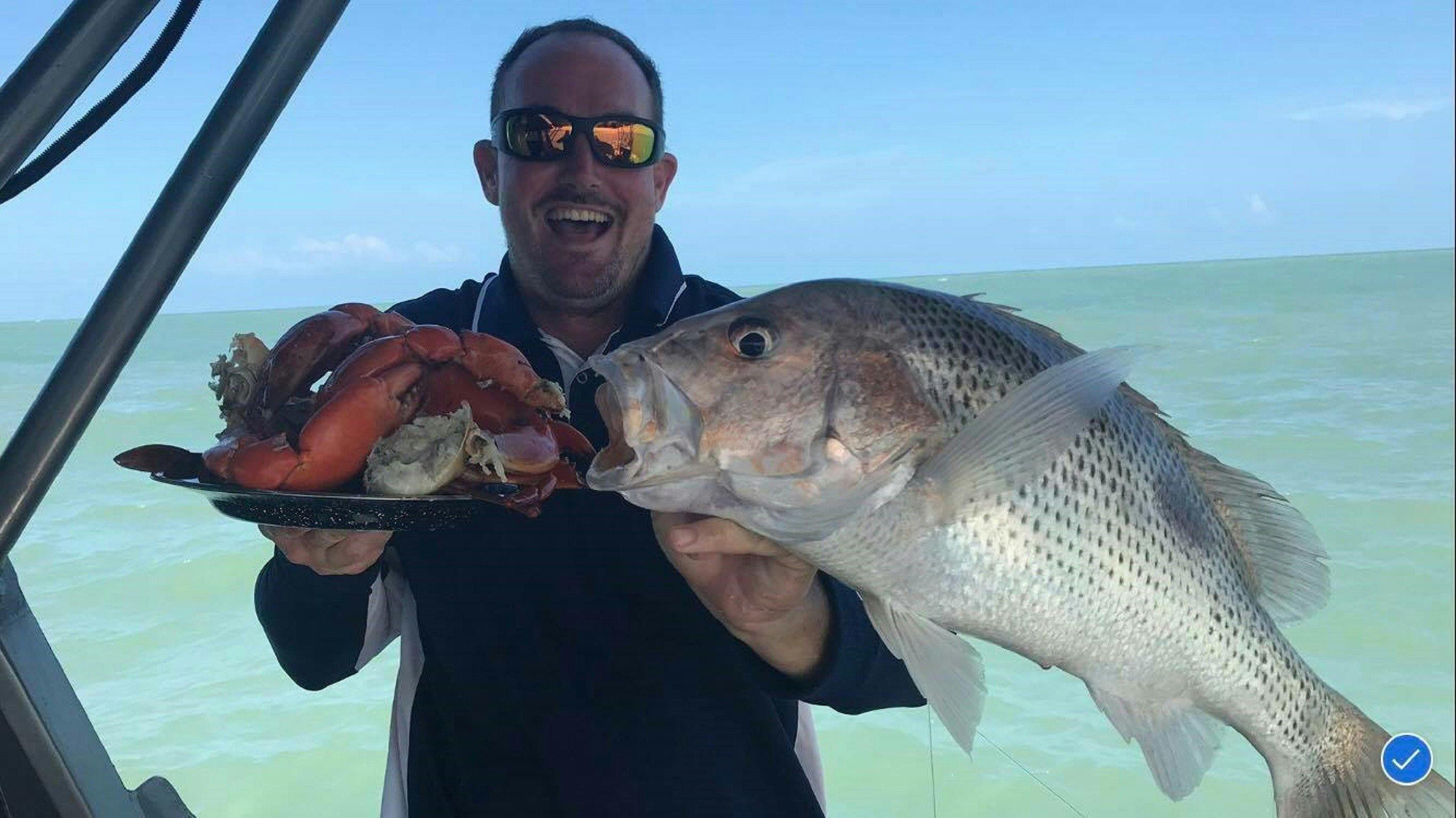 Man holding Goldies and Mud Crabs at Offshore Boats