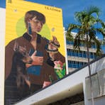 A huge mural with a yellow background, showing a woman with a large dog