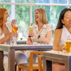 Two ladies sharing a cocktail and chatting