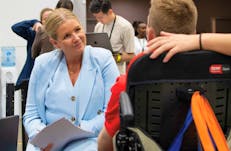 A lady in a light blue suit interviewing a young man looking for employment