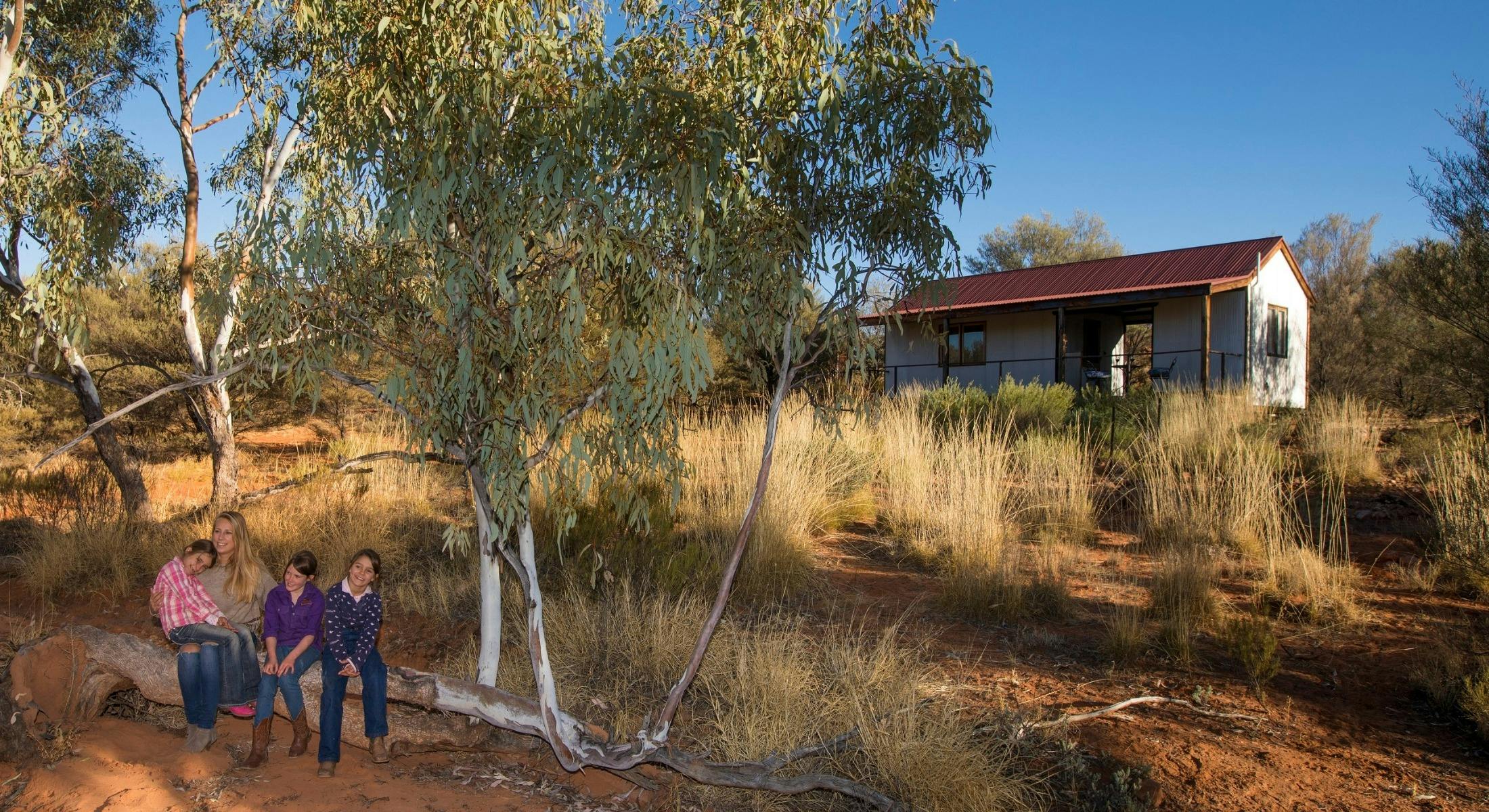 Family in front of cabin in bush setting at Ooraminna Homestead