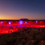 Purple trees and red landscape overlooking Uluru and the Outback during sunrise