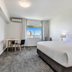 Spacious guest room with king bed, window view, and modern furnishings.