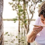 A woman smelling paperbark freshly harvested from a tree in the Northern Territory