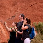 A group of friends look up at Uluru, entranced by the stories their audio guide is telling them.