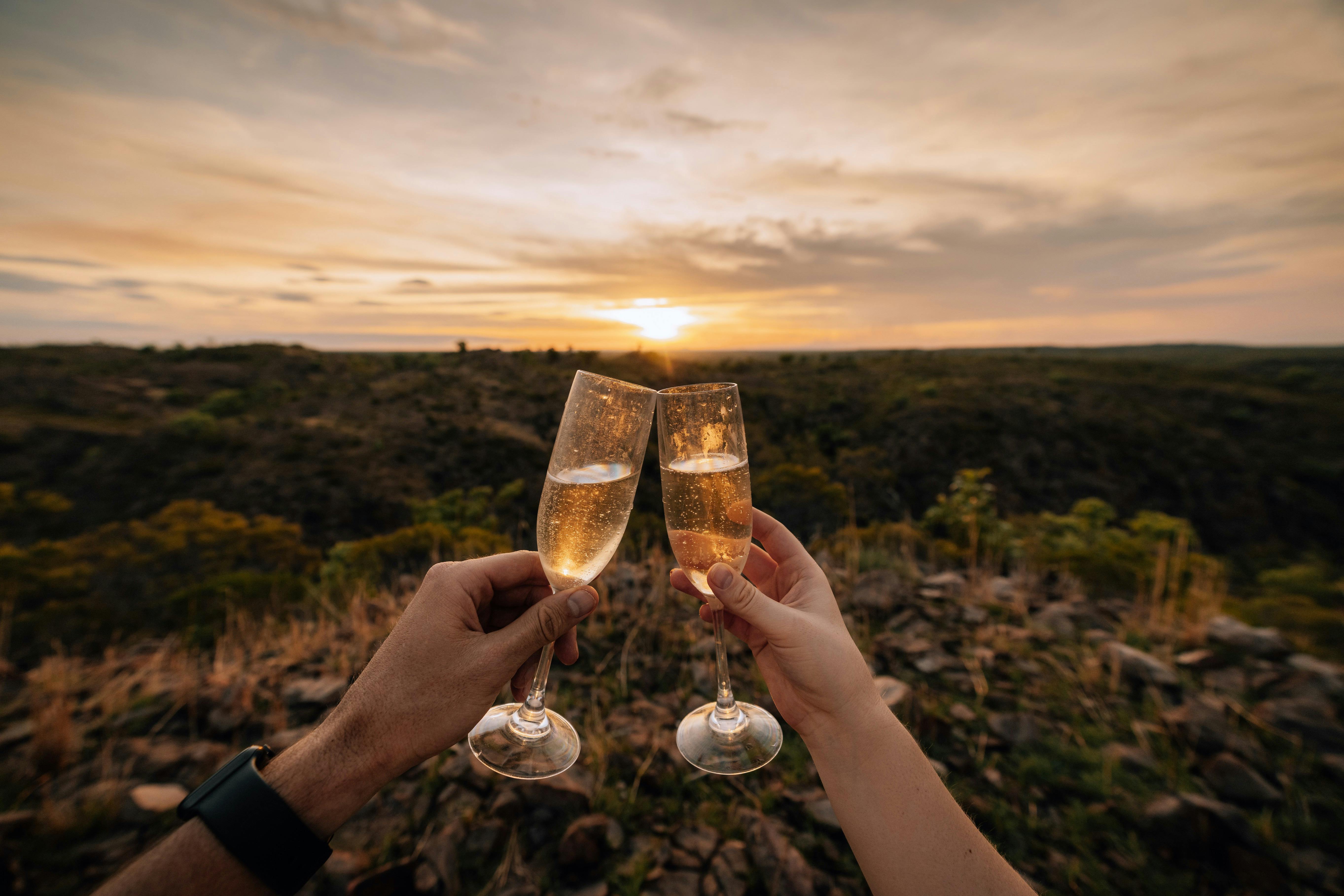 photo of champagne glasses clinking at sunset