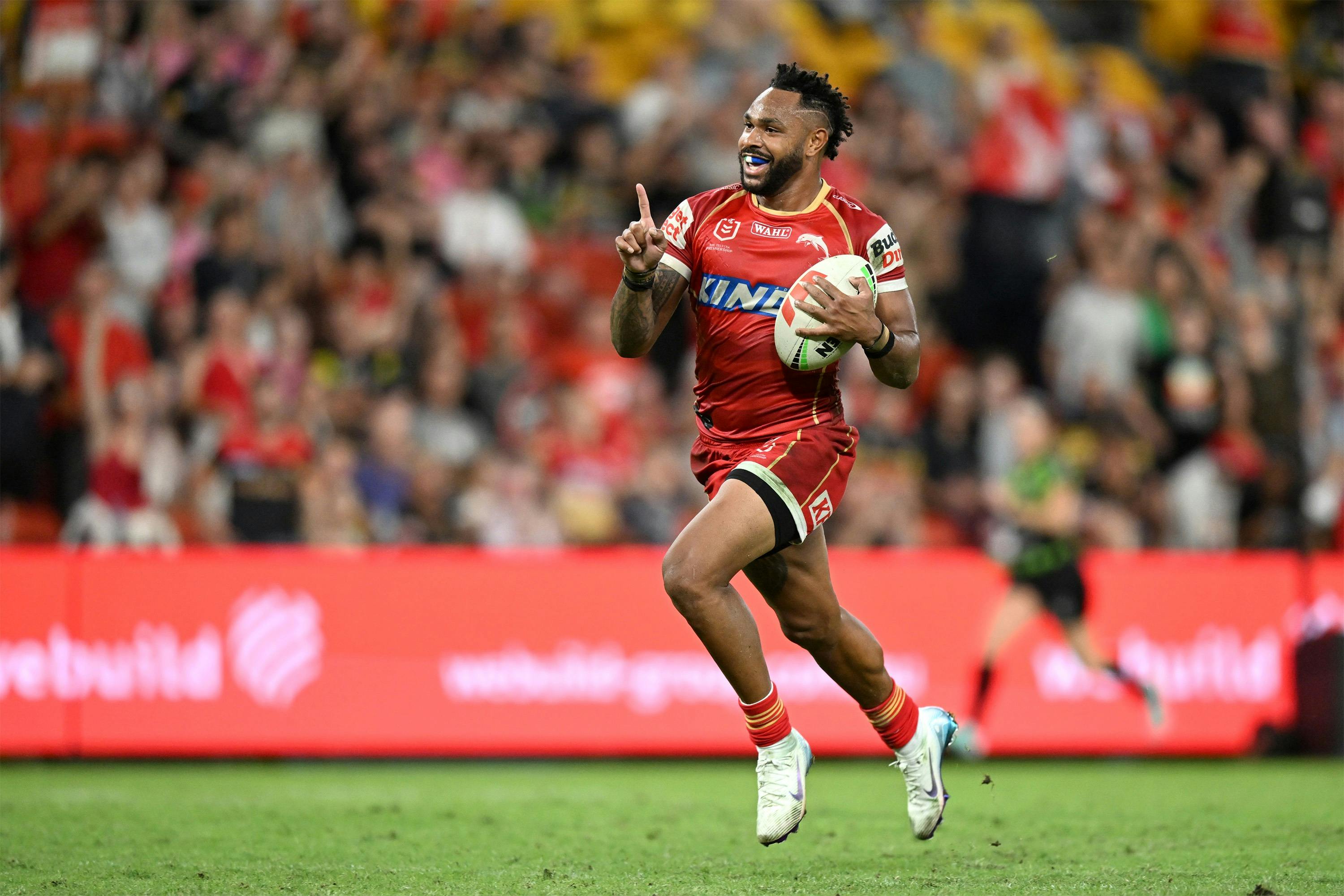 Dolphins player running on the field with ball under one arm and finger pointed up on the other
