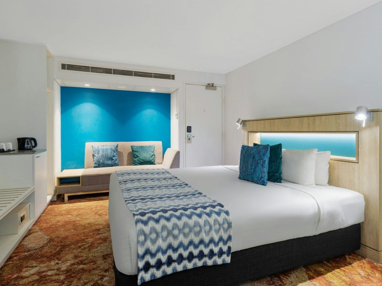 Bed with a blue blanket and cushions, expansive room