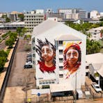 Mural of two Indigenous children on a large building, image taken from a drone