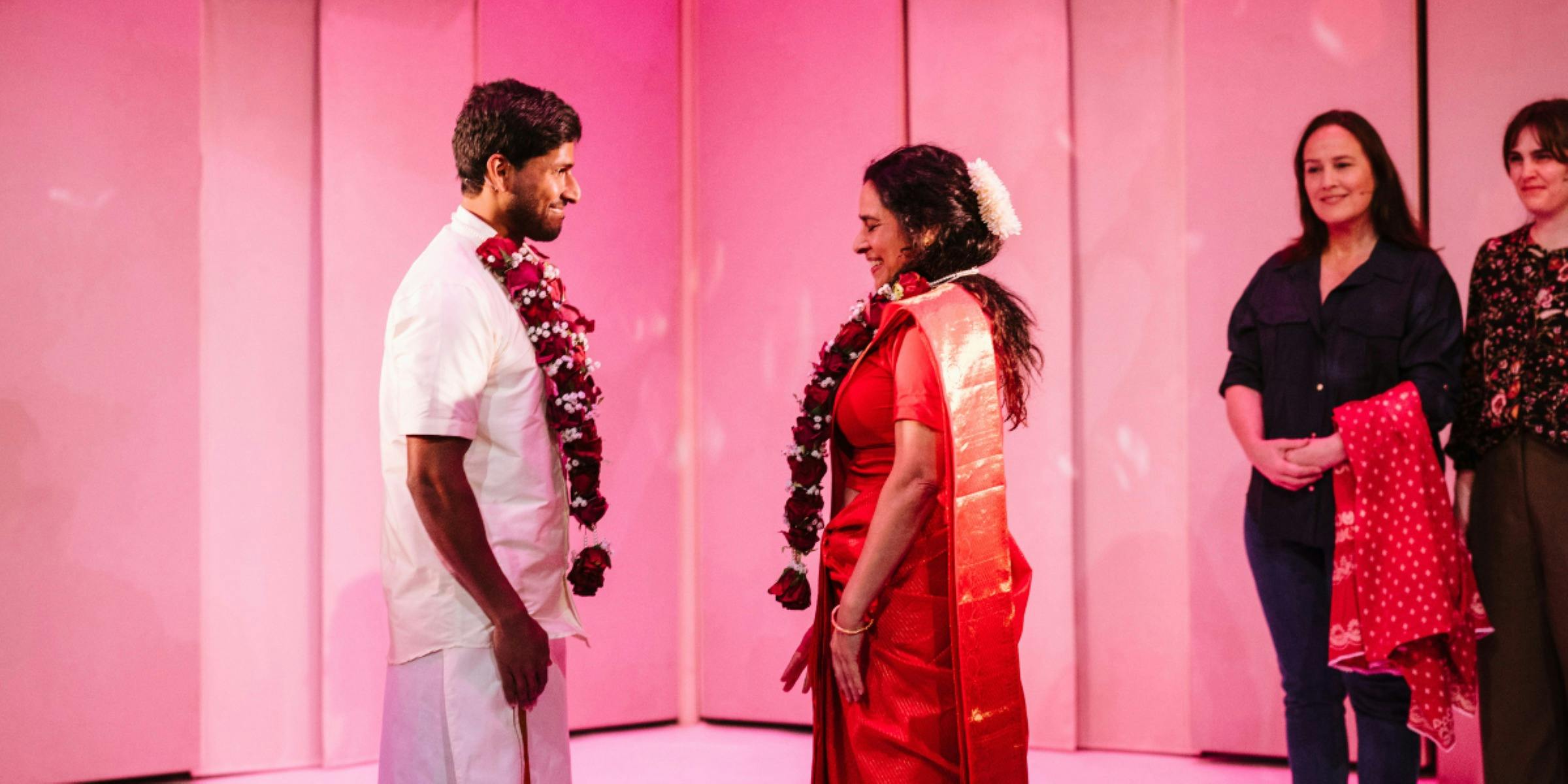 Man and woman with flower garlands around their necks, looking at each other lovingly.