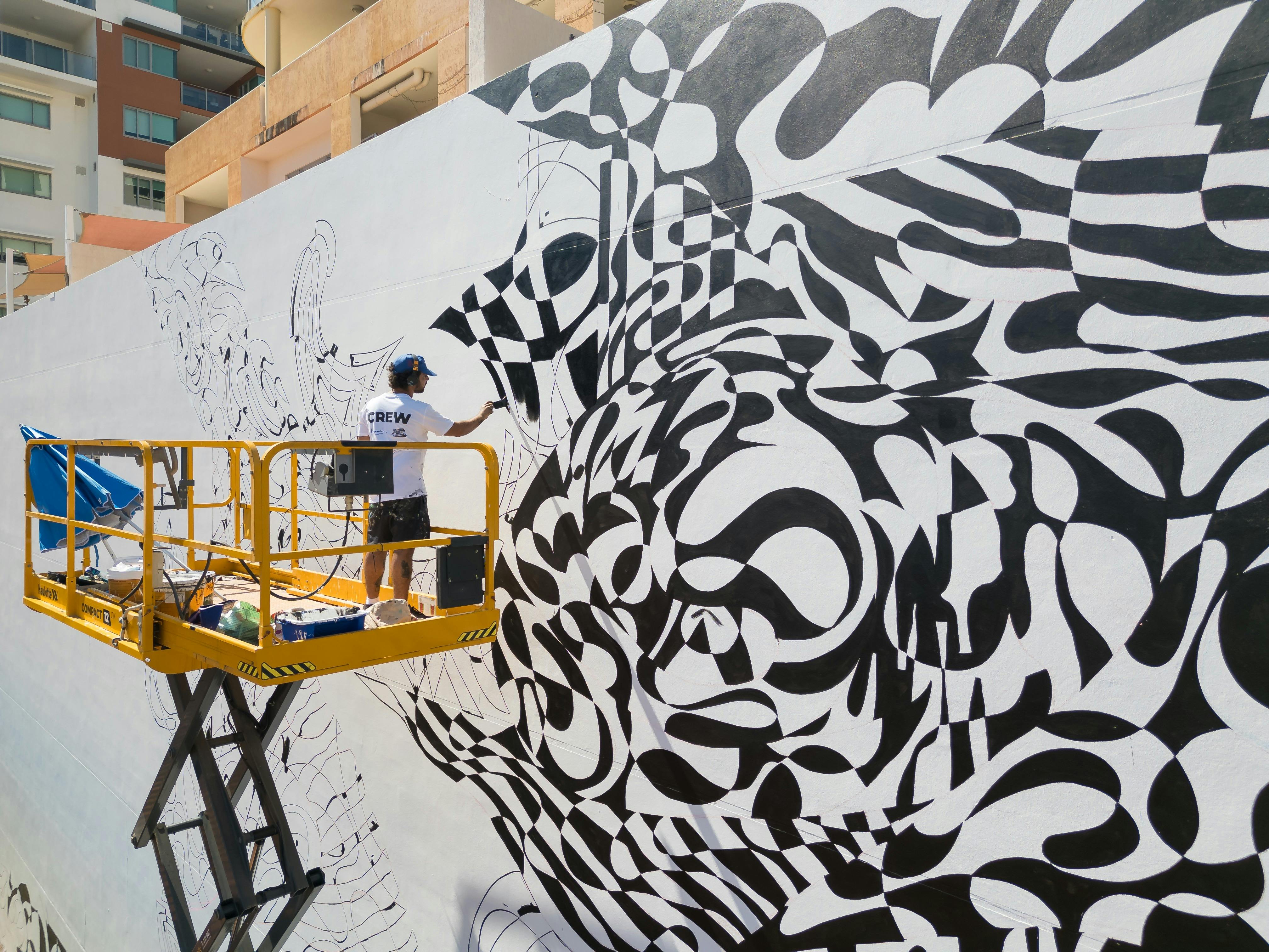 Artist on a scissor lift painting a monochrome pattern