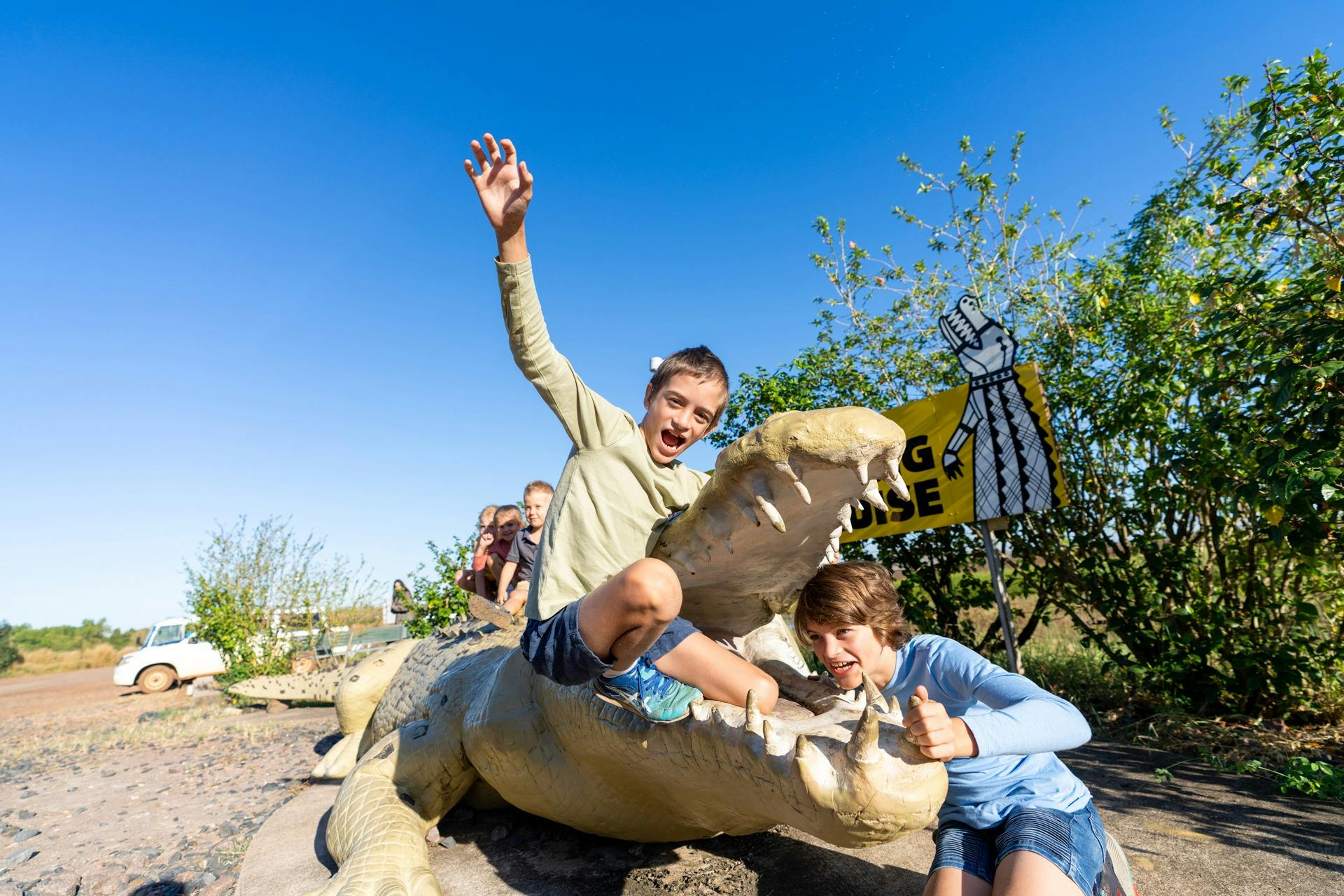 Two young boys posing in the mouth of a large crocodile statue
