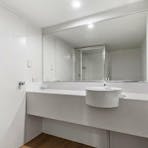White bathroom with vanity, mirror, and shower area.
