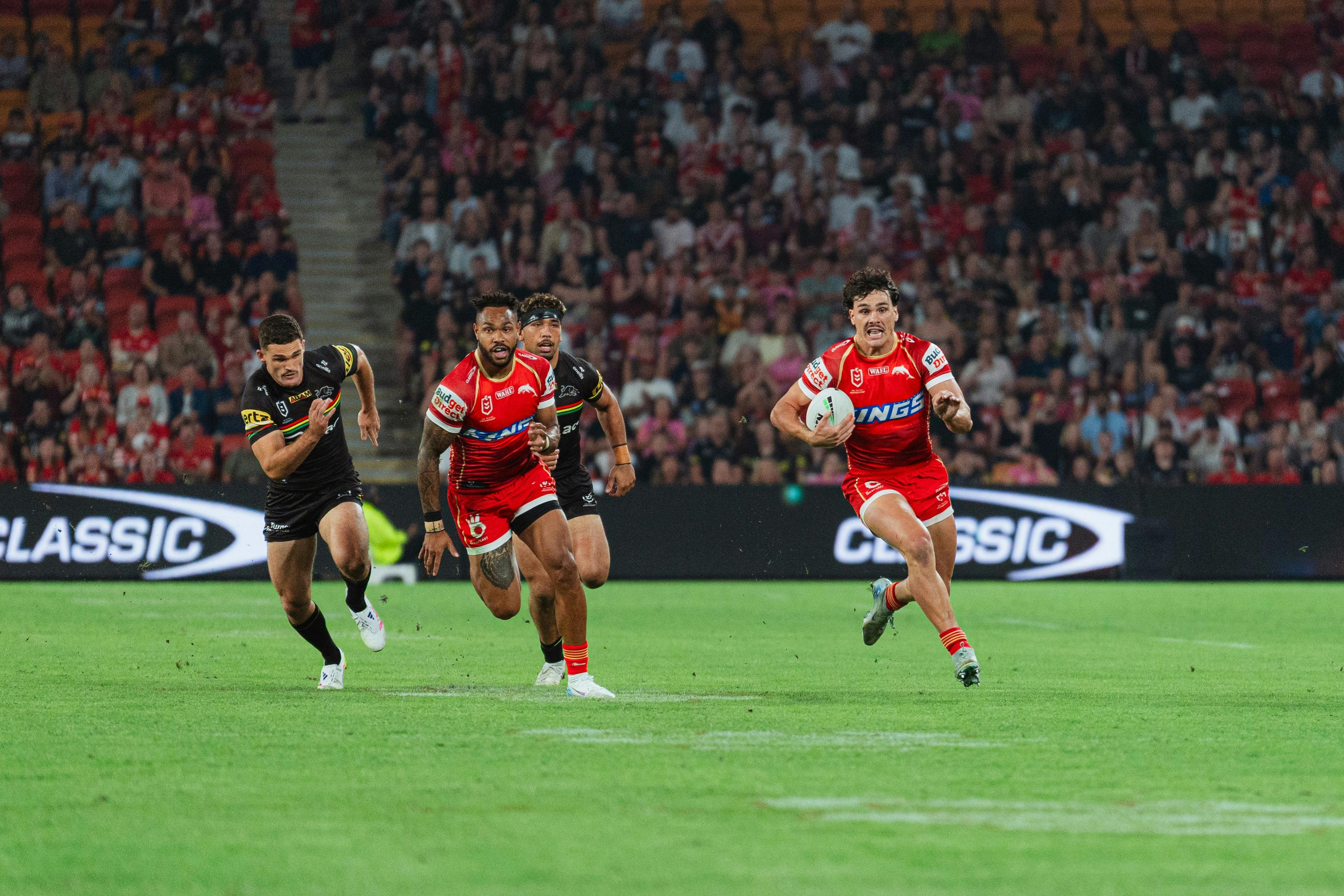 Dolphins player with ball running away from two Panthers players
