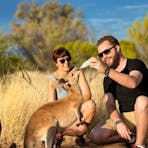 Visitors feed a kangaroo joey.