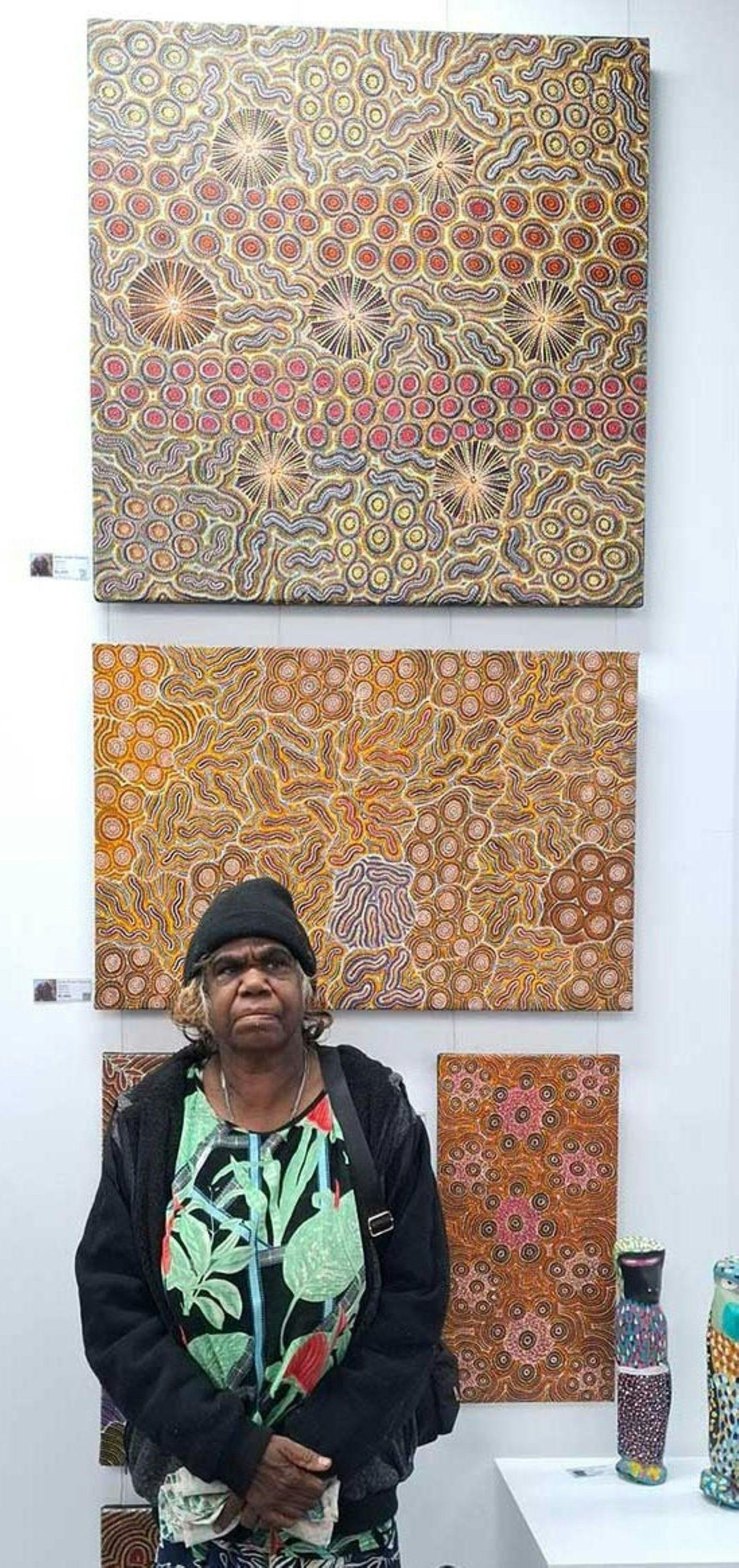 Annie Hunter standinf in front of her artwork on the feature wall